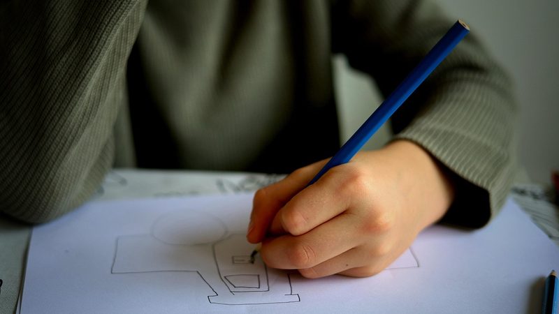 小学生の子どもが父の日メッセージを一生懸命書いているイメージ